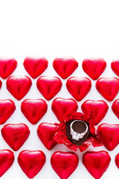 Bombons de chocolate em forma de coração embrulhados em papel alumínio vermelho para o dia dos namorados.