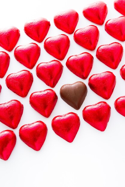 Bombons de chocolate em forma de coração embrulhados em papel alumínio vermelho para o dia dos namorados.