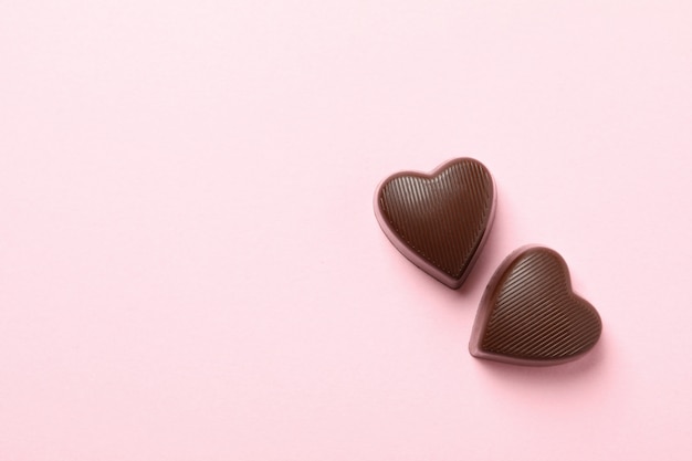 Bombons de chocolate em forma de coração no fundo rosa