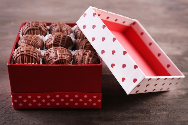 Bombons de chocolate em linda caixa de presente em fundo de madeira, close-up