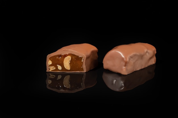 Bombons de chocolate em uma superfície escura com reflexo. Recheio de nozes e frutas. Copie o espaço.