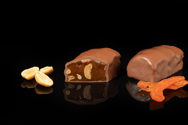 Bombons de chocolate em uma superfície escura com reflexo. Recheio de nozes e frutas. Copie o espaço.