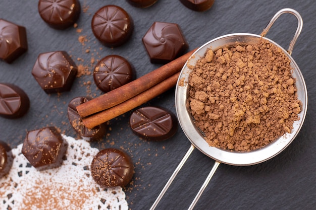 Bombons de chocolate em uma superfície preta, cacau em pó. foto escura, humor.