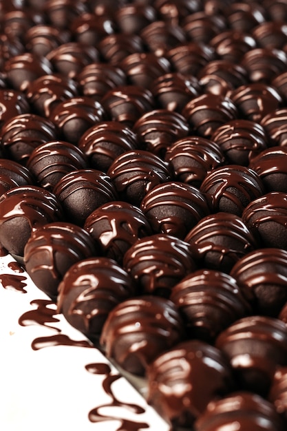 Bombons de chocolate redondos. Fundo escuro, sobremesa de luxo, chocolate escuro, feito à mão. Foto vertical.