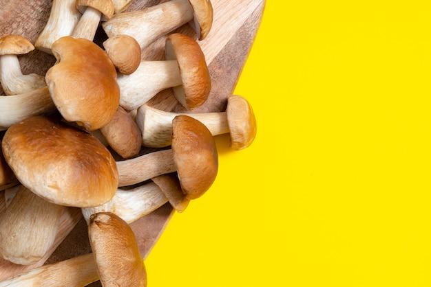 Boné marrom Boletus Edulis em uma placa de corte em fundo amarelo. Cogumelos comestíveis em uma prancha de madeira na cozinha. Ninguém