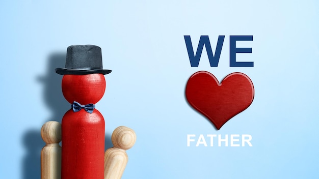 Boneca de madeira vermelha com um chapéu preto e gravata com um coração vermelho e texto We Love Fathers