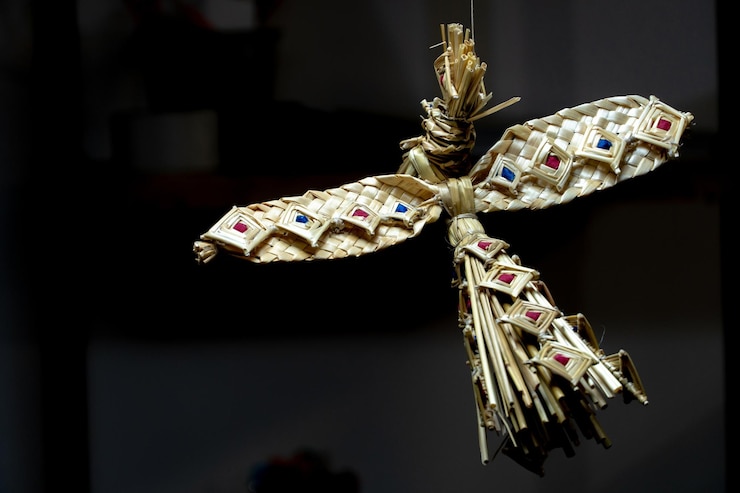 Foto boneca de palha tecelagem de palha brinquedo infantil de materiais naturais anjo com asas penduradas no ar contra um fundo preto criatividade e arte