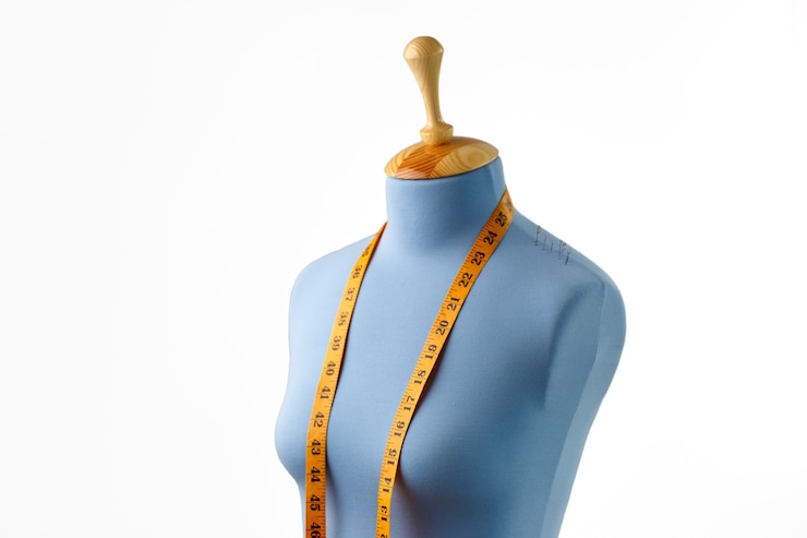 Foto boneco de alfaiate azul com fita métrica isolada no branco.