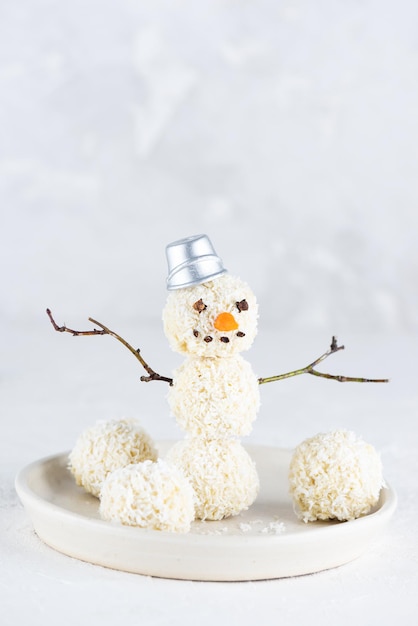 Boneco de neve alegre feito de trufas veganas de coco em um fundo claro