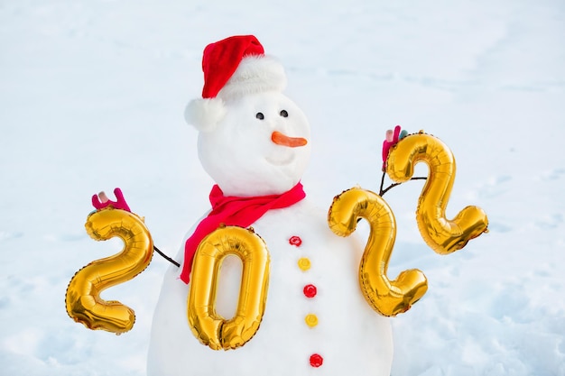Boneco de neve decorado com figuras do próximo ano novo e caixas de presente em sua base em um dia de inverno.