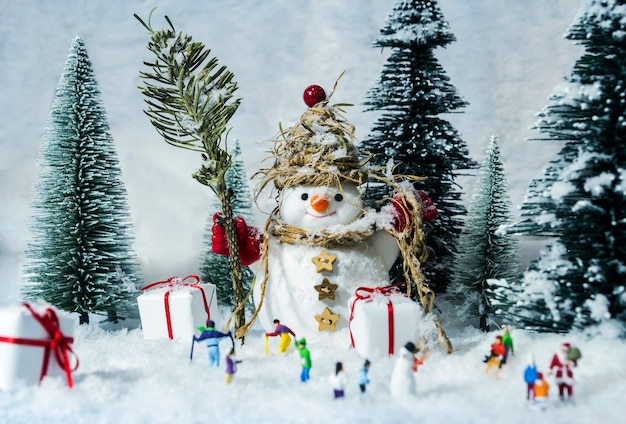 Boneco de neve e pessoas em bosques de pinheiros durante o inverno