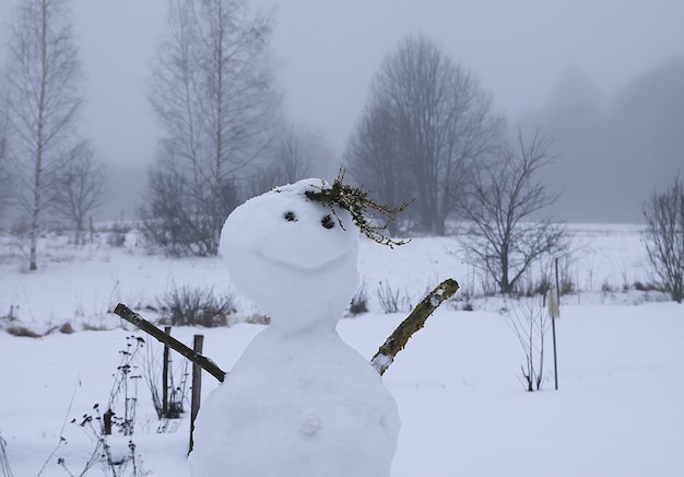 Boneco de neve engraçado feito por crianças em um campo rural coberto de neve