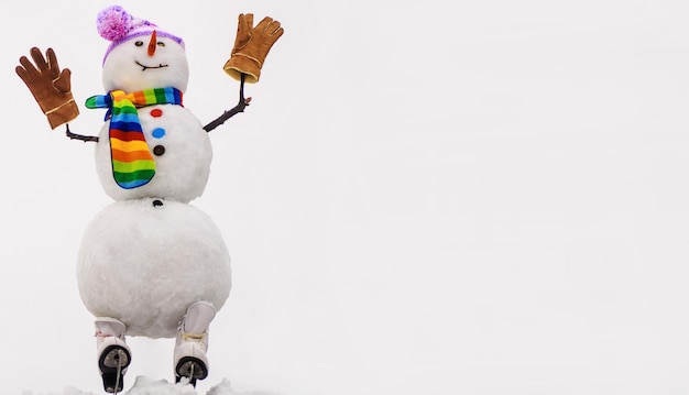 Foto boneco de neve feliz em luvas de lenço de chapéu na patinação no gelo, acenando as mãos feliz natal e feliz ano novo