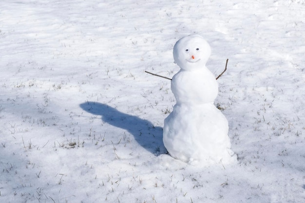 Boneco de neve no fundo branco Grama verde crescendo Primeira neve