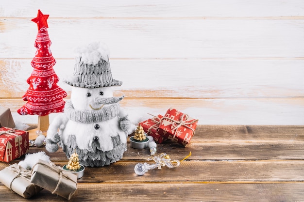 Boneco de neve pequeno com caixas de presente na mesa