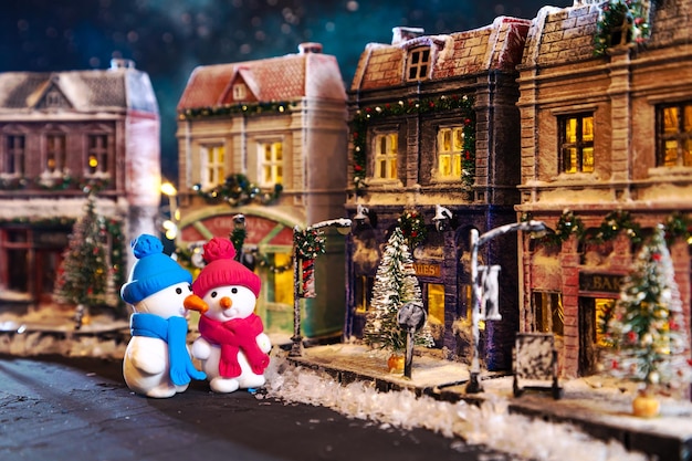 Bonecos de neve em uma rua coberta de neve noturna decorada para casas de brinquedos decoradas caseiras de Natal