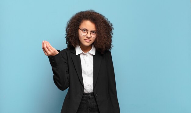 Bonita adolescente afro haciendo capice o gesto de dinero, ¡diciéndote que pagues tus deudas !. concepto de negocio humorístico