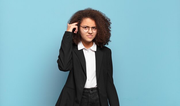 Bonita adolescente afro que se siente confundida y perpleja, mostrando que estás loco, loco o loco. concepto de negocio humorístico