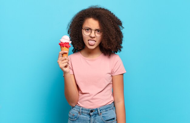 Bonita adolescente afro que se siente disgustada e irritada, sacando la lengua, disgustando algo desagradable y asqueroso. concepto de helado sumer