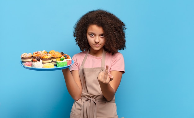 Bonita adolescente afro que se siente enojada, molesta, rebelde y agresiva, moviendo el dedo medio, contraatacando. concepto de panadero humorístico