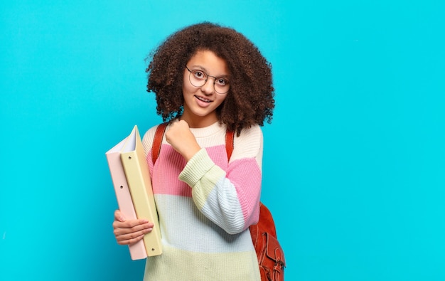 Bonita adolescente afro que se siente feliz, positiva y exitosa, motivada al enfrentar un desafío o celebrar buenos resultados. concepto de estudiante