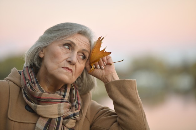 Bonita anciana triste en el fondo de otoño