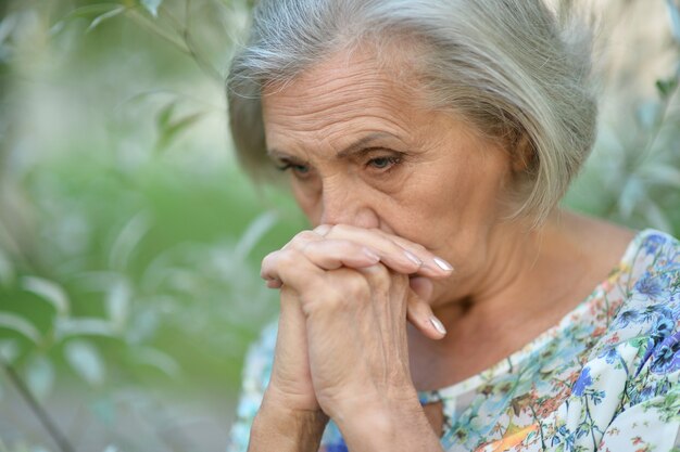 Bonita anciana triste en el fondo de primavera