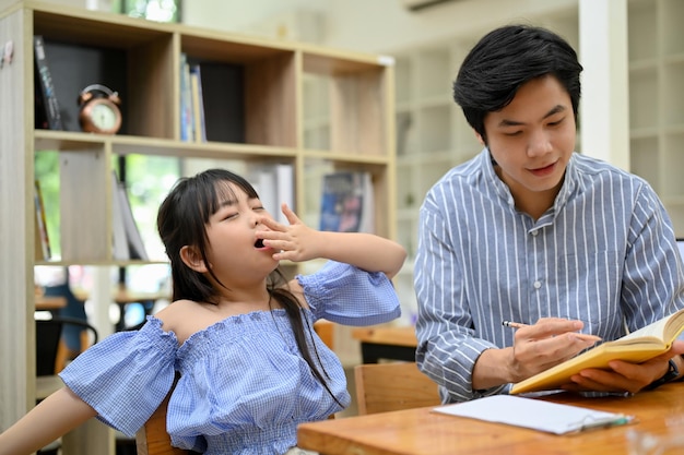 Bonita chica asiática bostezando mientras su tutor privado enseña matemáticas en el café