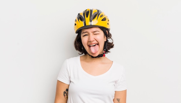 Bonita chica hispana con actitud alegre y rebelde bromeando y sacando la lengua concepto de bicicleta