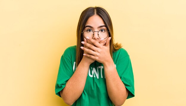 Bonita chica hispana cubriendo la boca con las manos con un concepto de ecología impactado