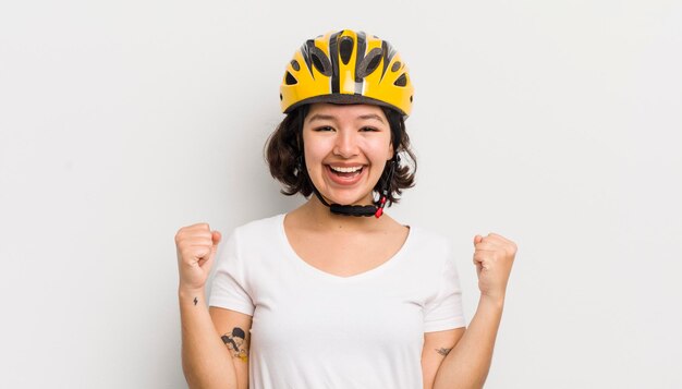 Bonita chica hispana sintiéndose sorprendida, riendo y celebrando el concepto de bicicleta de éxito