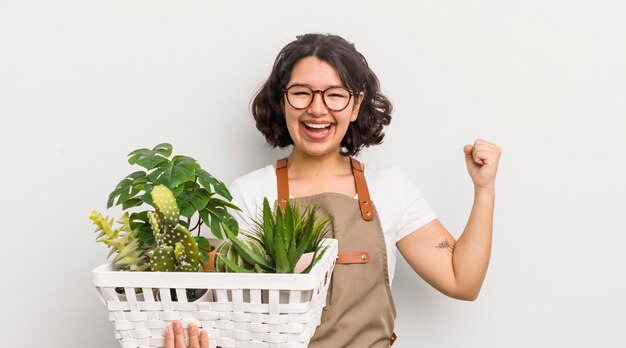 Bonita chica hispana sintiéndose sorprendida, riendo y celebrando el concepto de plantas de éxito