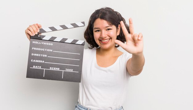 Foto bonita chica hispana sonriendo y luciendo amigable mostrando el concepto de cine número tres