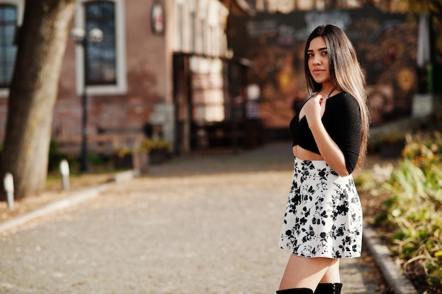 Bonita chica modelo latina de Ecuador vestida con tops negros y falda posada en la calle