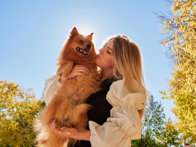 Bonita chica rubia juega con perro Pomerania