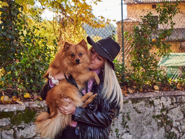 Bonita chica rubia juega con perro Pomerania