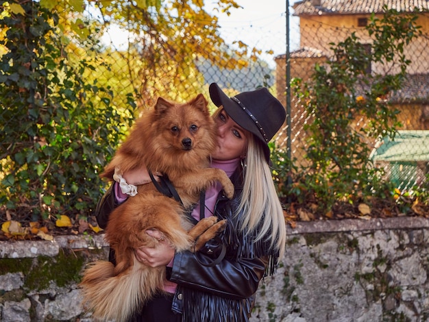 Bonita chica rubia juega con perro Pomerania