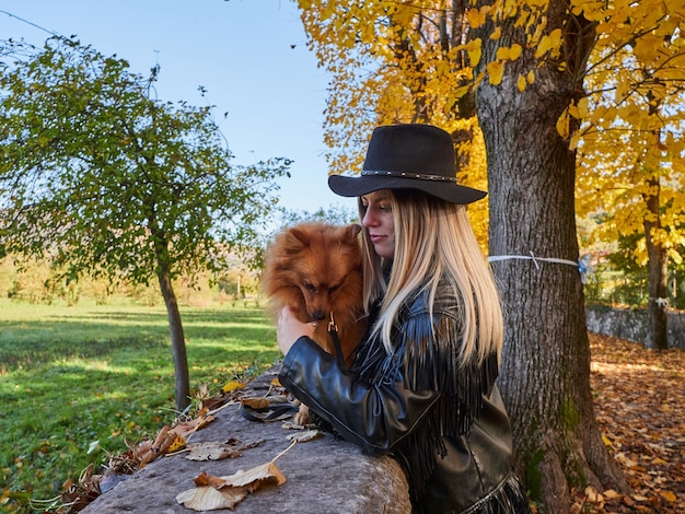 Bonita chica rubia juega con perro Pomerania