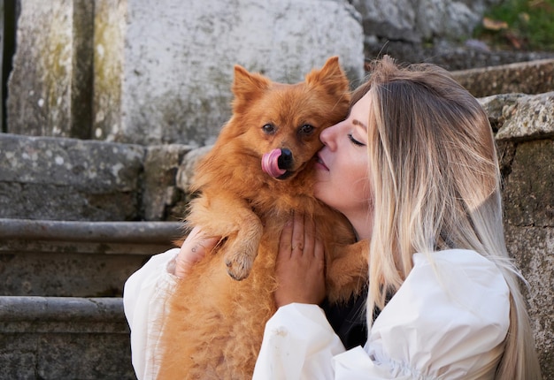 Bonita chica rubia juega con perro Pomerania