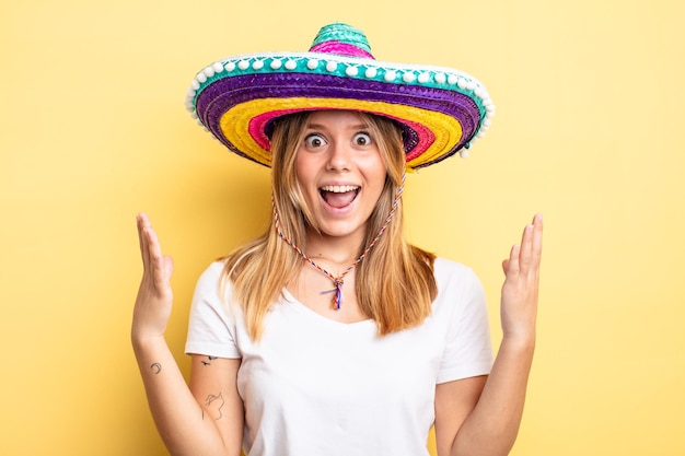 Bonita chica rubia que se siente feliz y asombrada por algo increíble. concepto de sombrero mexicano