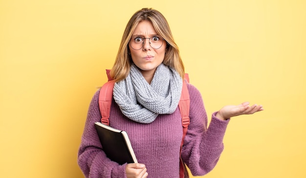 Bonita chica rubia que se siente perpleja, confundida y dudando. concepto de estudiante