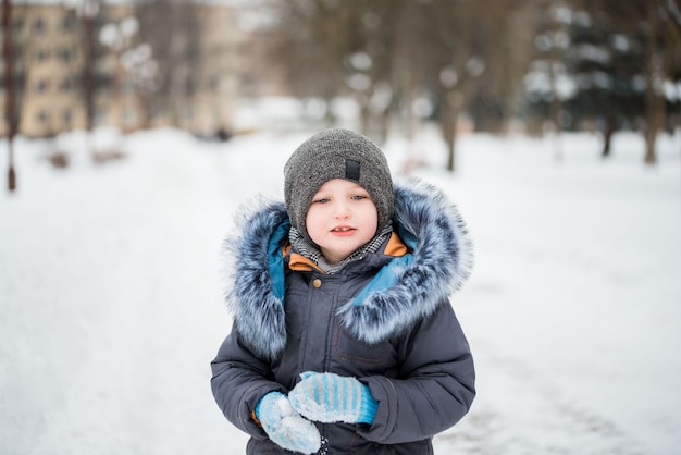 Bonita criança engraçada em roupas de inverno colorido se divertindo com neve,