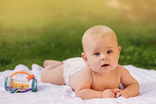 Bonita criança feliz deitado sobre um cobertor na grama ao ar livre no verão