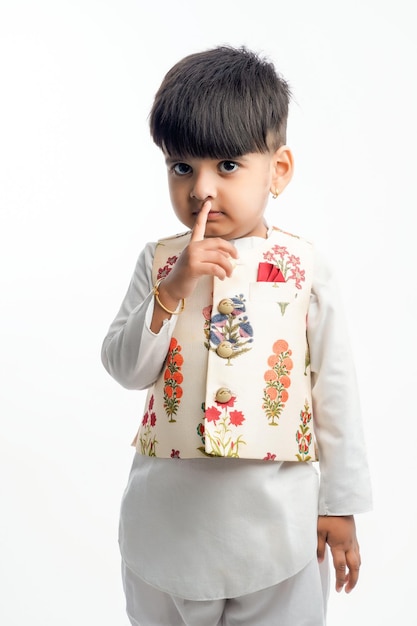 Bonita criança indiana em roupas étnicas e mostrando expressão sobre fundo branco