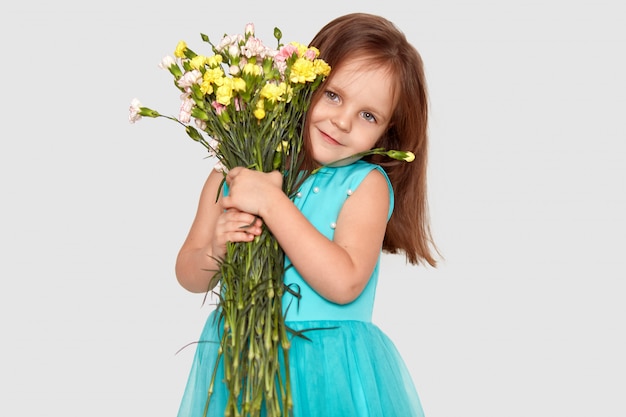 Bonita criança pequena abraça buquê de flores