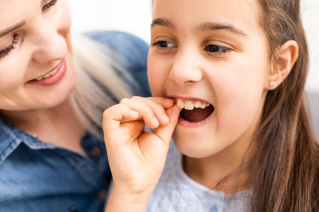 Bonita criança segurando o dente que pode estar solto ou dolorido.