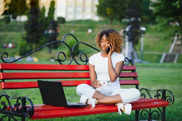 Bonita dama afroamericana con una computadora en el parque