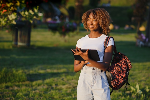 Bonita dama afroamericana con tablet PC en el parque