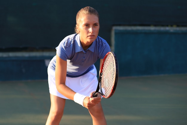 Bonita deportista con raqueta en la cancha de tenis. Estilo de vida saludable.