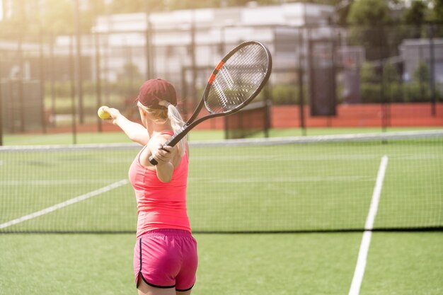 Bonita deportista con raqueta en la cancha de tenis. Estilo de vida saludable